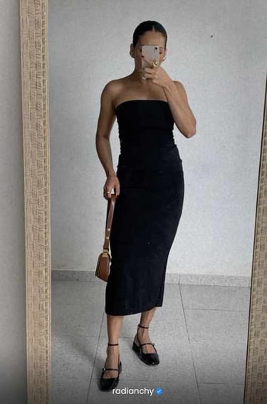 a woman in a black dress standing in front of a mirror