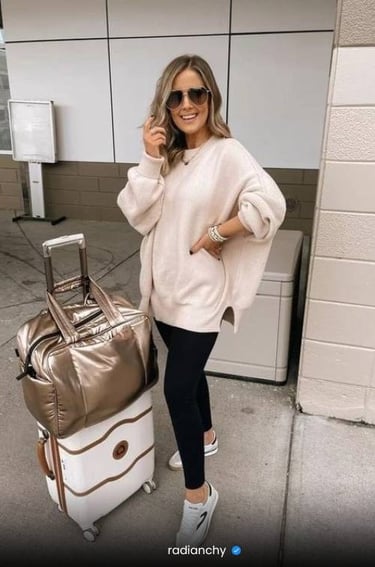 a woman in a white sweater and black leggings and a suitcase