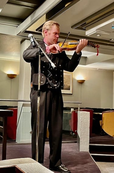 A man in black bunad playing a hardanger violin