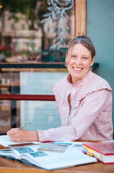 a woman sitting at a table with a pen and paper