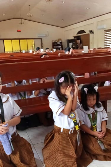 Elementary students praying in a school chapel on a wooden church bench