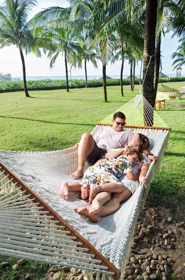 Семья отдыхает в гамаке под пальмами в Radisson Blu Resort Phu Quoc