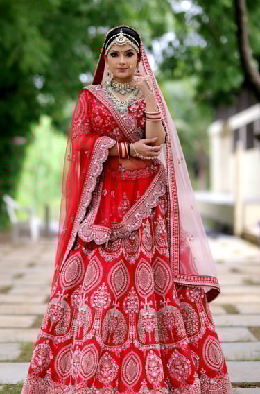 Traditional Indian bride in red lehenga with heavy jewelry, maang tikka, and flawless bridal makeup.