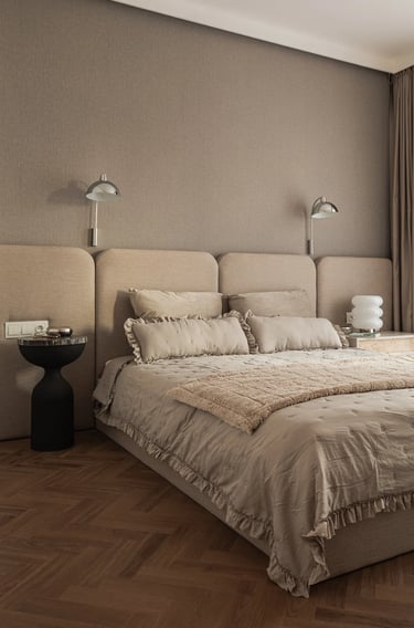 Fotograf wnętrz: beżowa sypialnia, panele tapicerowane na całą ścianę i parkiet jodełka.