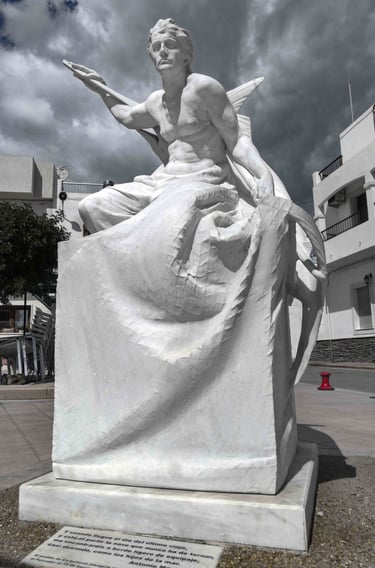 White marble sculpture depicting a fisherman holding a swordfish under a cloudy sky in Carboneras.