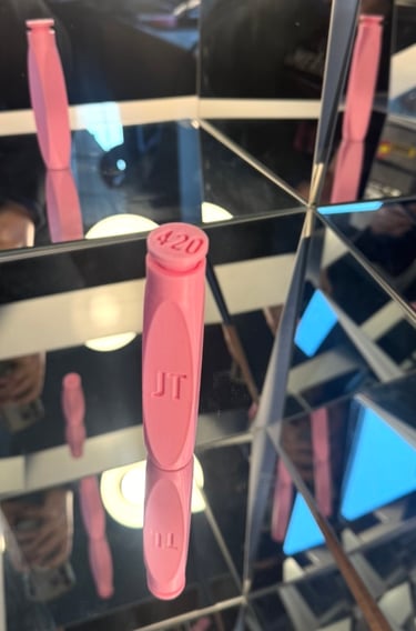 Pink 420 branded cannabis accessory standing on a mirrored surface with multiple reflections.