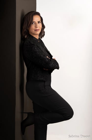 a corporate woman in a black shirt and black pants leaning against a wall