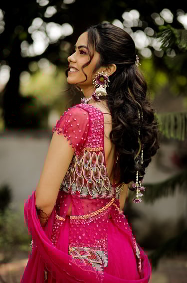 Bridal hairstyle with soft curls and floral accessories for haldi function by makeup artist in Gotri