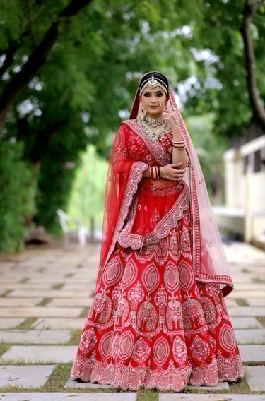Traditional Indian bride in red lehenga with heavy jewelry, maang tikka, and flawless bridal makeup.
