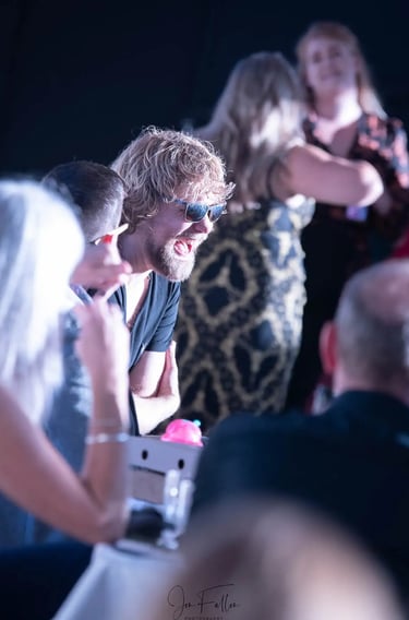 Smiling man with blonde hair and sunglasses enjoying a social event or party with friends.