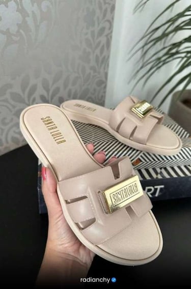 a person holding a pair of shoes with a gold buckle