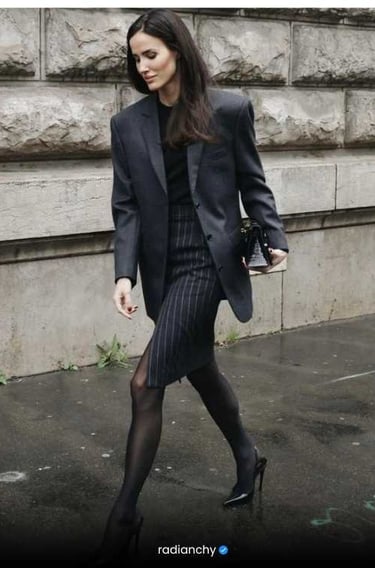 a woman in a suit and heels walking down a street