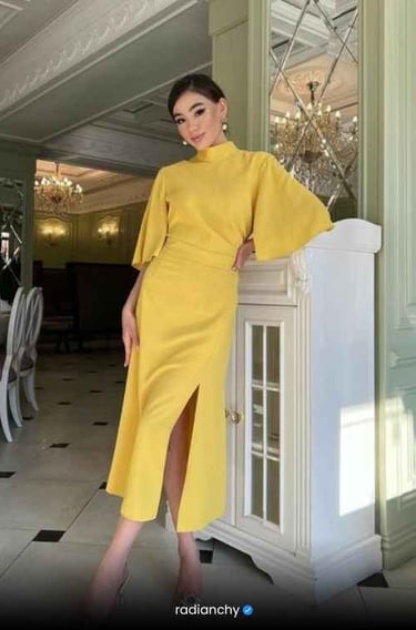 a woman in a yellow dress standing in front of a cabinet
