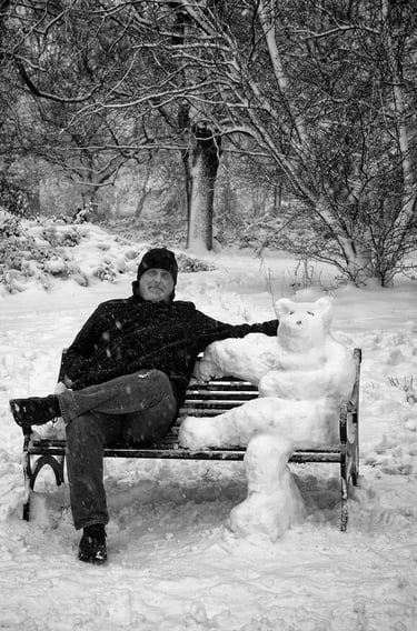 Man sitting on a bench next to a snow bear