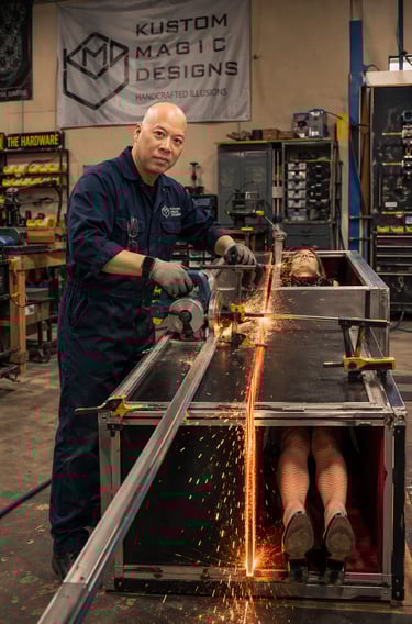 IRay Lum at Kustom Magic Designs uses a power saw to cut a magic box in half with sparks flying.