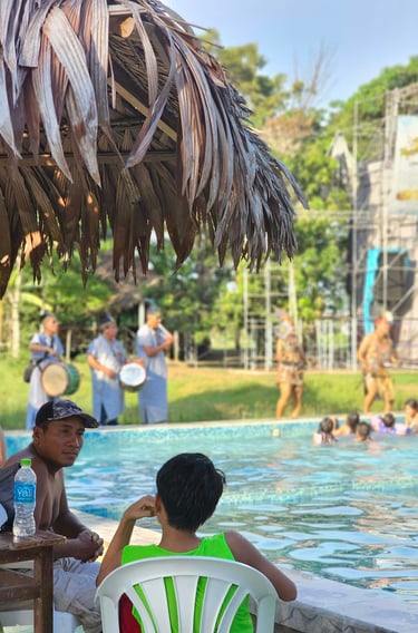 Guests relax by a tropical swimming pool during a live music performance with traditional dancers.