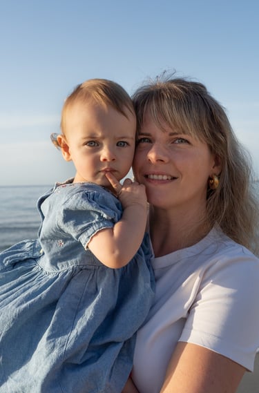 mère tenant sa fille dans les bras sur la plage 