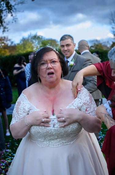 A bride in an off-the-shoulder lace wedding dress adjusting her gown at an outdoor wedding reception.