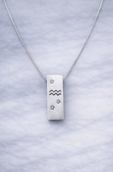 Handmade 999 silver Aquarius zodiac necklace with a vertical bar pendant on a marble surface.