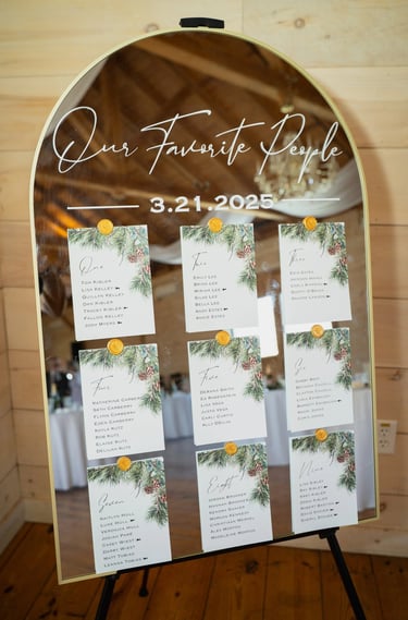 Elegant gold arched mirror wedding seating chart with pine needle cards and wax seals.