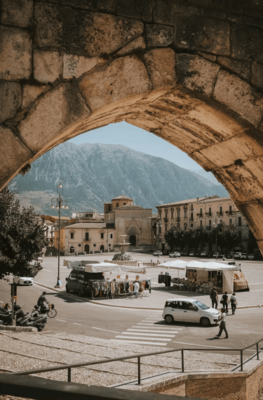 Veduta della piazza principale di Sulmona attraverso un arco in pietra