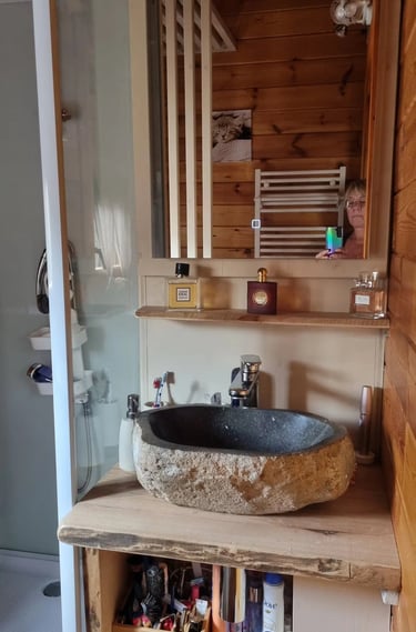 un lavabo de salle de bain avec une vasque en pierre et un meuble-lavabo en bois