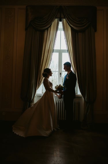 vestuvių fotosesija dvaro viduje. a bride and groom standing in front of a window