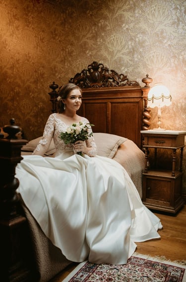 a bride in a white wedding dress sitting on a bed. boudoir
