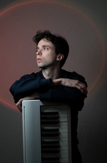 Arnavall debout appuyé sur un piano, de face