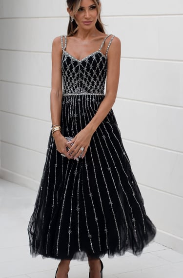 Woman in an elegant black evening gown with silver detailing.