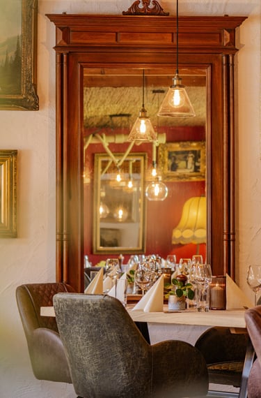 Elegant restaurant dining table with wine, glasses, and floral decor in a cozy, rustic setting with natural light and