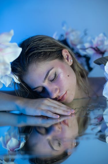 Primer plano de modelo rubia con maquillaje de sirena y reflejo de agua en espejo