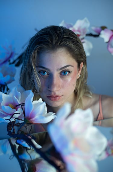 Modelo con maquillaje de sirena, reflejo de agua en espejo y decorada con flores en estudio