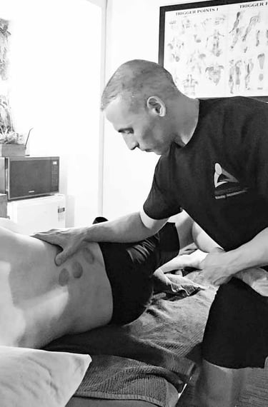 Male massage therapist performing Myofascial Stretching of the leg and back massage