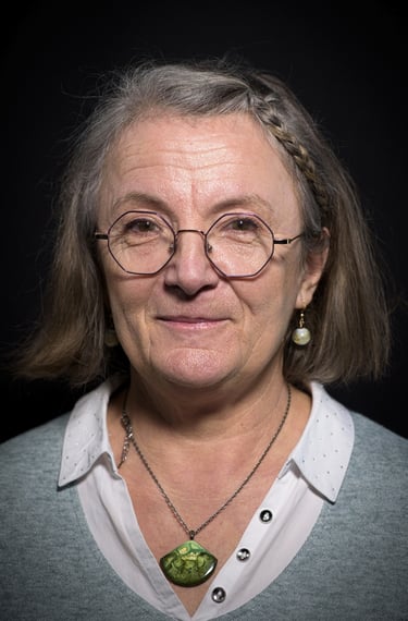 a woman with glasses and a necklace with a green pendant