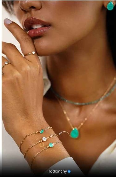 a woman wearing a white shirt and green jewelry