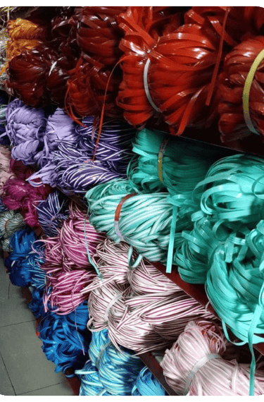 Bundles of multi colored recycled plastic weaving strips neatly stored and ready for handmade woven bag production.
