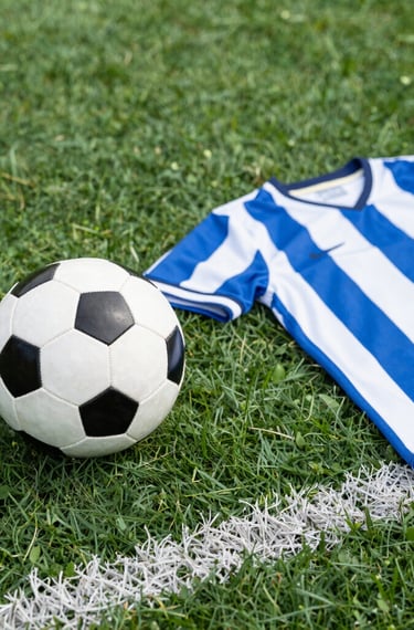 A collection of colorful soccer jerseys is laid out, each featuring distinctive team logos and color patterns. The jerseys include stripes, stars, and various shades, providing a rich visual contrast.
