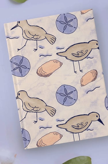 a notebook with a sand piper bird and seashells on it