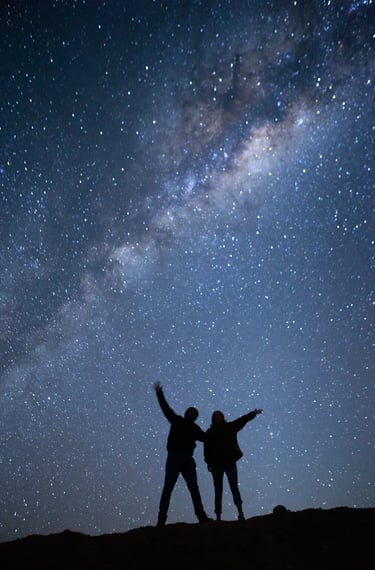 two people standing on a hill with their arms up