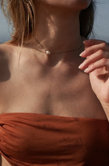 a woman in a red dress and a necklace with pearls