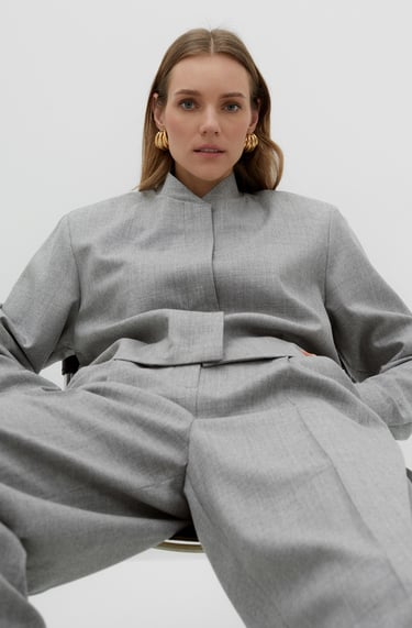a woman in a grey suit and earrings