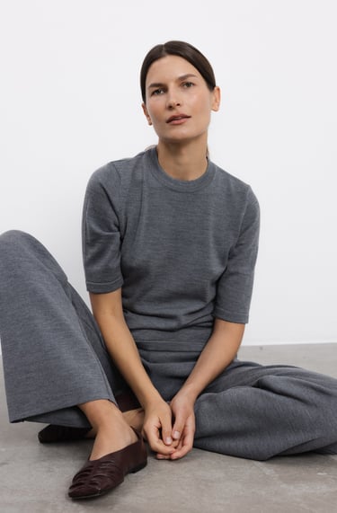a woman sitting on the floor in a grey sweater