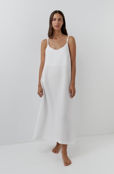 a woman in a white dress standing in front of a white wall