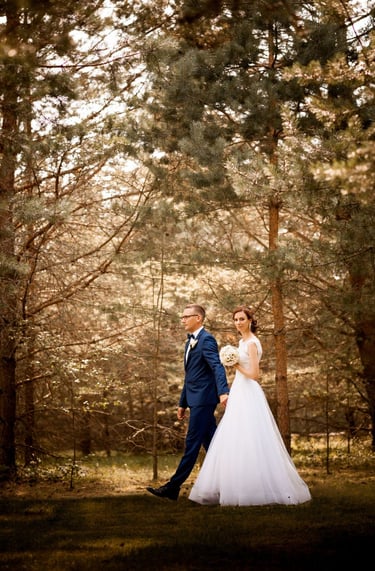 a bride and groom walking through a wooded area