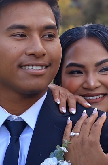 A smiling bride embraces her groom from behind, resting her hands on his chest to show her wedding r