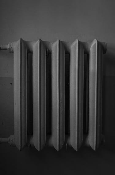 Monochrome image of a cast iron radiator against a wall.