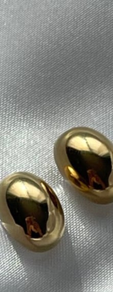 a pair of gold earrings with a white fabric