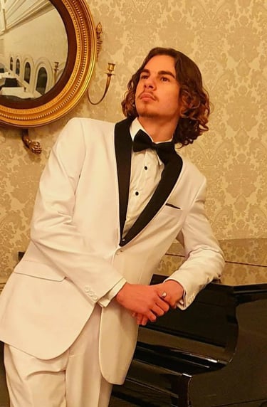 a man in a white suit and a piano