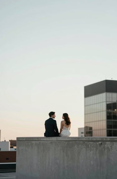 A candid, high-end photograph of a couple sharing a quiet moment on a minimalist rooftop in a North American city. The sky is a pale white and the architectural lines are clean and sharp, reflecting a sophisticated and professional style.